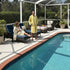Two people in Fouta Spa bath robes by a poolside with outdoor furniture and plants.
