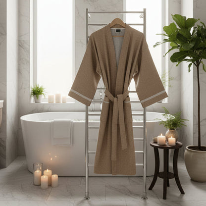 Taupe Natte Fouta bathrobe on a stool next to a white bathtub in a bathroom.→ Fouta Bath Robe in Taupe - Handmade Tunisian Cotton Lightweight Robe | The Fouta Spa

